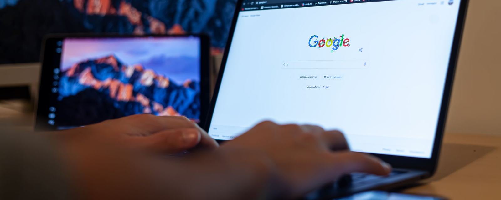 Çalışma masasında Google arama sayfası açık dizüstü bilgisayar ve monitör
